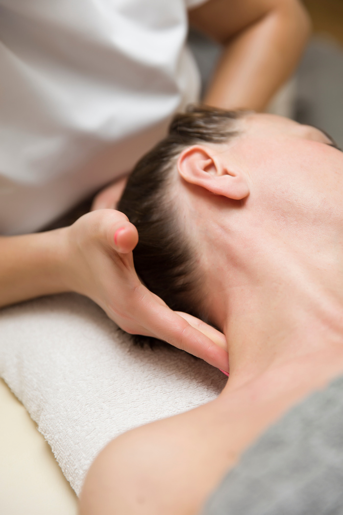 Woman getting a stress relieving pressure point massage on her neck by a health therapist